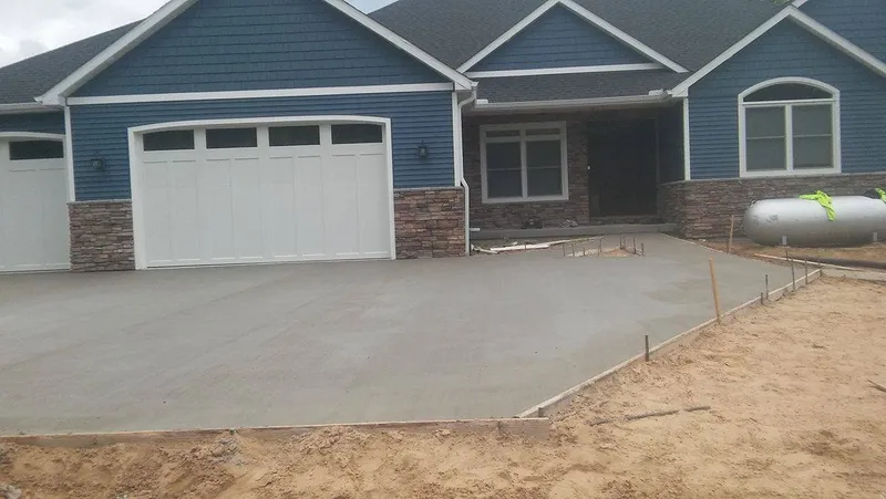 Concrete driveway at a blue craftsman home with stone accents