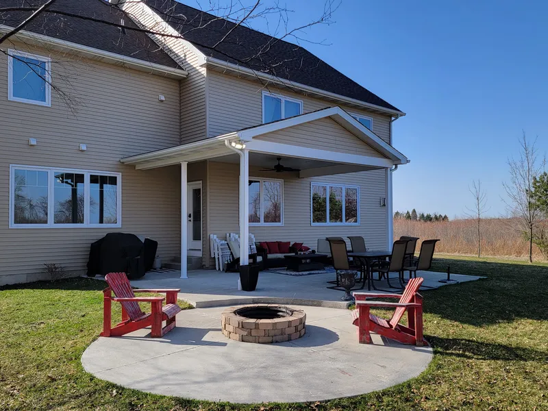 Concrete patio with built-in fire pit and seating behind a Mid-Michigan home