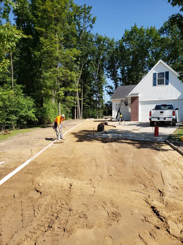Concrete crew grading and preparing the compacted base before a driveway pour