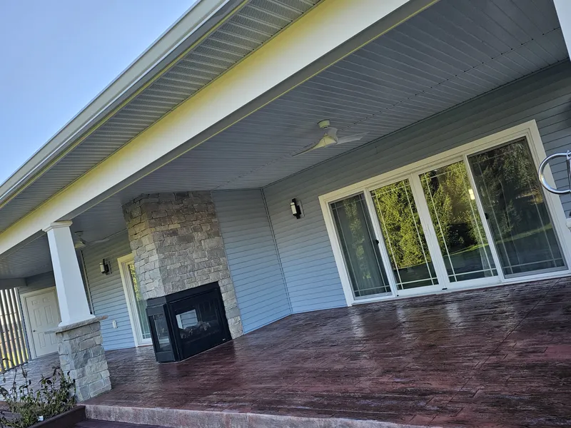 Rich brown stamped concrete patio under a covered porch with a stone fireplace