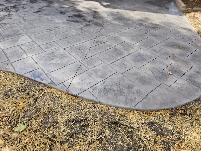 Gray slate-pattern stamped concrete patio with a curved decorative border